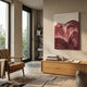 A modern living room features a leather chair, wooden cabinet, books, and the Giant Sculptures Terralune Red Layered Ridge 3D Wall Art on the wall. Large windows fill the space with light and reveal a balcony with greenery outside.