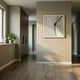 A modern hallway with wooden floors, neutral walls, sunlight streaming through a window, and a potted plant on the sill features the LineaFlux Black Thread Warp Geometric 3D Wall Art by Giant Sculptures as a framed abstract accent.