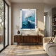 A modern living room showcases the Vivexa Blue Wave Textured Ocean Abstract 3D Wall Art by Giant Sculptures above a wooden console, next to a beige sofa and a large window that brightens the space.