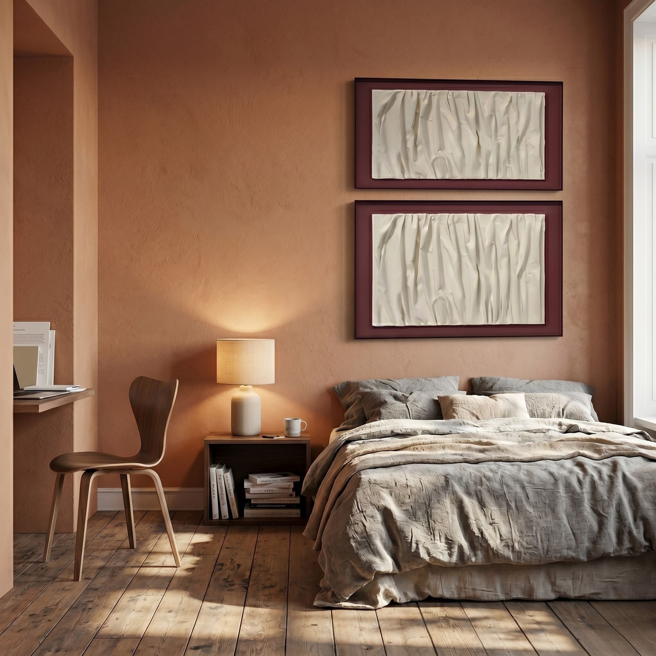 A cozy bedroom with earthy brown walls, a beige bed, a Foldara Cream & Burgundy Draped Paper Dual-Panel 3D Wall Art by Giant Sculptures above the bed, a bedside lamp, and a small desk with a wooden chair by the window.