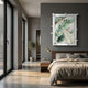 A modern bedroom featuring a neatly made bed, wooden nightstand, gold lamp, Giant Sculptures’ Verdantia I Green & Gold Leaf Textured 3D Wall Art on a gray wall, floor-to-ceiling windows, and a potted plant beside an open closet.