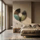 A modern, minimalist bedroom features the Giant Sculptures Vortaryn Teal Patina & Bronze Circle Sculptural 3D Wall Art above the bed, neutral bedding, a wooden nightstand with lamp and cup, and floor-to-ceiling windows flooding the room with light.