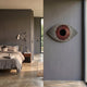 A modern bedroom with gray walls, a neatly made bed, and the Aurevion Maroon Radiant Eye 3D Wall Art by Giant Sculptures above the headboard. Soft natural light enters, enhancing the cozy feel and highlighting this striking contemporary decor piece.