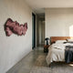 Vellun Wave Clay Rouge Sculptural Hand-Painted 3D Wall Art by Giant Sculptures, mounted on a cream wall in a modern bedroom with a walnut bed and concrete floor.