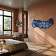 Vellun Wave Deep Marine Sculptural Hand-Painted 3D Wall Art by Giant Sculptures, a folded blue-and-white striped ribbon form mounted on a terracotta bedroom wall.