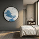 Yunsei Blue Temple Ridge Round Silk Relief 3D Wall Art by Giant Sculptures mounted on a grey bedroom wall above a linen-dressed bed and wooden bookshelf.