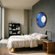 Aurelios Midnight Blue Crystal Porcelain & Gold Orbit 3D Wall Art by Giant Sculptures mounted on a grey bedroom wall above a linen bed and bookshelf.