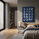 Orbivelle White & Cobalt Patch Sphere Panel 3D Wall Art by Giant Sculptures, displayed above a nightstand and bed in a modern grey bedroom.
