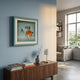 Cavallero Aqua Cigar Tools & Metal Ashtray Framed Wall Art mounted on a blue wall above a walnut sideboard with design books, vase, and lamp.