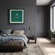 Cavallero Green Cigar & Cutter Framed Wall Art by Giant Sculptures hung above a bed with grey and blue linens in a modern dark-walled bedroom.