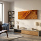 Bristella Ember Gold Textured Linear Panel 3D Wall Art mounted above a concrete console in a modern living room with bookshelf, lamp, and armchair.