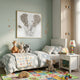 Blossomkin Elephant 3D Floral Wall Art by Giant Sculptures in a gold-trimmed frame, displayed above a child's bed with plush toys and an alphabet rug.