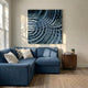 Rillora Blue Ribbed Wood Carving 3D Wall Art by Giant Sculptures mounted above a blue sectional sofa in a sunlit living room with wood flooring and a walnut side table.