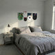 ReelRiot Comic Legends Record 5-Panel Wall Art by Giant Sculptures displayed above a grey bed in a minimal bedroom, featuring green, white, red, and black vinyl record panels with comic character prints.