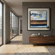 Aerolith Blue & Earthy Abstract Textured Framed Wall Art by Giant Sculptures hung above a walnut console in a modern hallway with floor-to-ceiling windows.