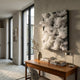 Chromavolt Frosted White Cluster Straw 3D Wall Art mounted above a wooden desk with books, vase, and lamp in a sunlit modern hallway.