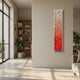 Aeraline Coral Bloom Vertical Gradient Leather 3D Wall Art mounted on a beige wall in a sunlit living room with a bookshelf and sofa nearby.