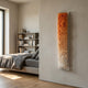 Aeraline Amber Fade Vertical Gradient Leather 3D Wall Art by Giant Sculptures, mounted on a beige wall beside a bedroom with a grey linen bed and bookshelf.