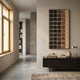 Quadrelle Midnight & Sand Grid Geometric 3D Wall Art mounted in a hallway above a dark sideboard with design books, beside a window and concrete floor.