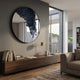 Erosian Midnight Stream Textured Round Mirror 3D Wall Art by Giant Sculptures, mounted above a walnut sideboard with books and brass lamp in a modern living room.