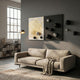 Spherium Black & Silver Orb Dual-Tone Panel 3D Wall Art by Giant Sculptures mounted above a beige sofa in a grey living room with a floor lamp and bookshelf.