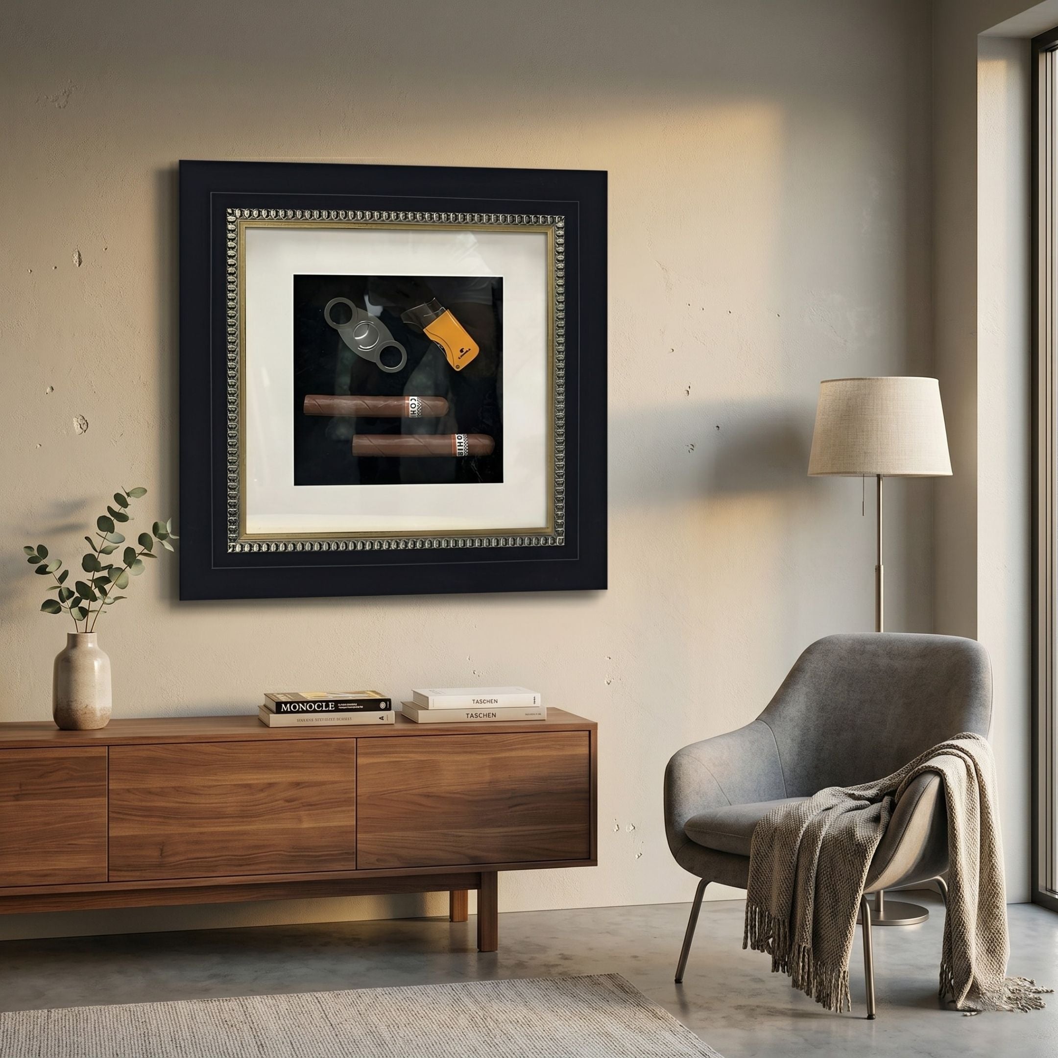 Havantra Double Cigar & Cutter Framed Wall Art by Giant Sculptures, displayed on a cream wall above a walnut sideboard with books, beside a grey armchair and floor lamp.