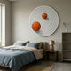 Orbiora III Orange Duo Concentric Sphere 3D Wall Art by Giant Sculptures displayed above a bed with blue linens, wood nightstand, and lamp in a minimalist bedroom.