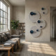 Orbiora Blue Orb 4-Panel Concentric Sphere 3D Wall Art by Giant Sculptures displayed on a beige wall in a modern living room with grey sofa and bookshelf.