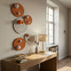 Orbiora Orange & White Orb 5-Panel Concentric Sphere 3D Wall Art by Giant Sculptures displayed above a wooden console table with lamp and books.