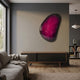 Veyora Magenta Bloom 3D Relief Wall Art by Giant Sculptures, glossy magenta starburst on black, mounted above a wooden sideboard in a modern living room.