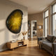 Veyora Golden Aura 3D Relief Wall Art by Giant Sculptures, an organic-shaped piece with a golden-yellow starburst and black border, mounted above a wooden console in a sunlit living room.