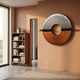 Zenithra Silver & Copper Dual-Tone Circular 3D Wall Art mounted on a terracotta wall beside a walnut bookcase in a sunlit modern living space.