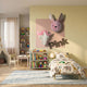 Animora Unicorn & Bunny Pink Kids Plush 3D Wall Art by Giant Sculptures mounted on a yellow wall above a child's bed in a pastel kids' bedroom.