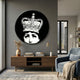 Lunoria Crowned Face Round Wood Embossed Wall Art mounted on a grey living room wall above a wooden console with books, vase, and blue armchair.