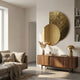 Aurargent Gold Textured Round Mirror 3D Wall Art by Giant Sculptures mounted above a walnut sideboard with pampas grass and brass lamp in a living room.