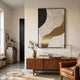 Aurista Gold Wave & Black Curve Cotton Spray Wall Art by Giant Sculptures displayed above a walnut sideboard with vase, books, and brass lamp in a sunlit living room.
