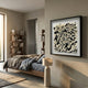 Petalus Black & Cream Layered Felt 3D Wall Art by Giant Sculptures in a black square frame, displayed in a modern bedroom beside a wooden bed and bookshelf.
