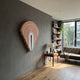 Arclune Coral & White Arc Sculptural Felt 3D Wall Art mounted on a grey wall in a modern living room with bookshelves, side table, lamp, and sofa.