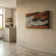 Waverno Ember & Graphite Flow Metal 3D Wall Art by Giant Sculptures mounted on a beige wall in a modern kitchen with a concrete island and shelving.