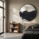 Erosian Obsidian Drift Textured Round Mirror by Giant Sculptures mounted above a wooden bookshelf in a modern bedroom with grey linen bedding and floor lamp.