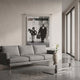 CineLuxe Léon The Professional Cinematic Poster Wall Art by Giant Sculptures displayed on a textured white wall in a modern living room with a grey sofa and metal coffee table, featuring a black and white acrylic print with advertising nail mounts.