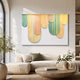 Dravena Pastel Cascade Ribbon 3D Wall Art by Giant Sculptures in pastel yellow, peach, and green, displayed above a cream sofa in a sunlit living room.