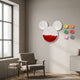 Blockform Mickey Capsule Acrylic 3D Wall Art by Giant Sculptures, clear Mickey-head capsule filled with red bricks, beside six coloured bricks above a lounge chair.