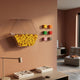 Blockform Hexagonal Capsule Acrylic 3D Wall Art by Giant Sculptures, a clear hexagonal capsule filled with yellow blocks beside six coloured block forms on a terracotta wall.
