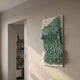 Avarin Turquoise Wave Swirl Acrylic Tile 3D Wall Art by Giant Sculptures mounted on a beige wall beside an open doorway leading to a bookshelf.