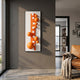 Orbevo White & Orange Sphere Vertical 3D Acrylic Wall Art by Giant Sculptures mounted on a grey wall beside a tan leather armchair in a modern living room.