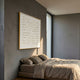 Linquora Grid Lines Gold Foil Acrylic 3D Wall Art by Giant Sculptures displayed above a linen-dressed bed in a grey-walled bedroom beside a tall window.