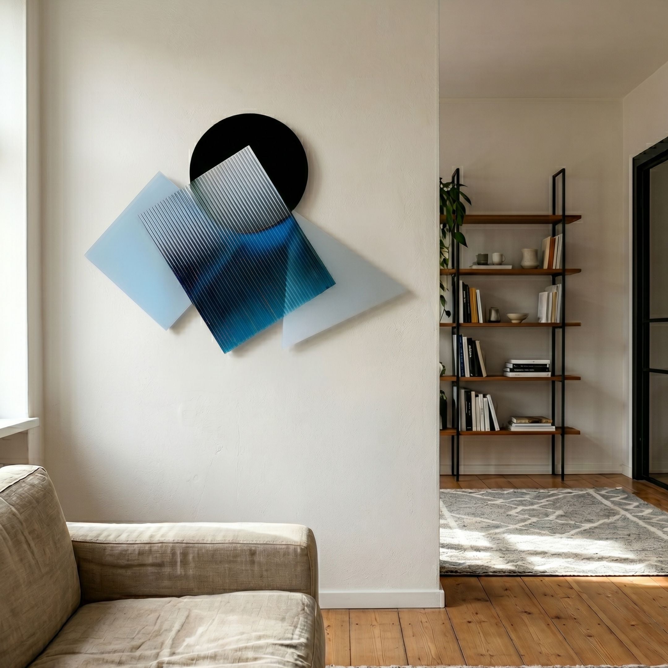 Orbigrad Blue Overlay Geometric Acrylic 3D Wall Art with black circle and translucent blue striped panels, mounted above a linen sofa beside a bookshelf.