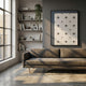 Stellure Slate Blue & White Folded Acrylic 3D Wall Art by Giant Sculptures displayed above a brown sofa in a sunlit living room with bookshelves.