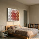 Dromara Rose Gradient Acrylic 3D Wall Art by Giant Sculptures mounted above a wooden bed in a beige plaster bedroom with bookshelf and nightstand.